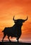Bull statue against orange sunset, Spain.