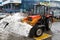 A bulldozer with a bucket full of snow standing in the parking near the shopping center `Domodedovo` in Moscow