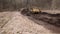 Bulldozer at construction site shovels soil into a heap. Powerful yellow earthmover crumbles sand