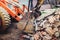 Bulldozer demolishing concrete walls of small building and gathering debri, loading into dumper trucks