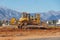 Bulldozer levels the ground in the urban area of a wasteland against the backdrop of mountains