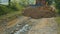 A bulldozer levels and repairs a road in the mountains. The bulldozer moves slowly and covers the stones on the road.