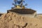 Bulldozer or loader moves the earth at the construction site against the blue sky. An earthmoving machine is leveling the site.