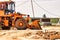 Bulldozer or loader moves the earth at the construction site against the blue sky. An earthmoving machine is leveling the site.