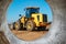 Bulldozer or loader moves the earth at the construction site against the blue sky. An earthmoving machine is leveling the site.