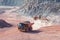 Bulldozer loading dumper truck with porphyry rock material in a