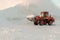 A bulldozer removes snow with a bucket after a blizzard.