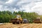 A bulldozer and a tractor compact the cut grass in a silage trench.