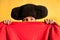 Bullfighter afraid with big hat hidden behind cape