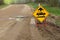 A bumpy road ahead sign with a large pothole