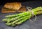 A bunch of asparagus with roasted pork tenderloin on the wooden cutting board