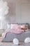 Bunch of balloons in elegant grey bedroom interior with king size bed with grey bedding and pink pillows and blanket