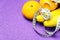 A bunch of bananas, tangerines and a measuring tape on a purple background