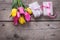 Bunch of bright yellow and pink spring tulips and boxes with presents on vintage wooden background.