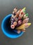A bunch of colorful pencils in a blue container in downward view