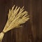 Bunch of compressed stems with ears. Golden wheat on dark brown wooden background