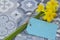 Bunch of daffodils narcissus tied with string with a blank blue tag on a tiled surface.  Spring Saint Davidâ€™s Day concept