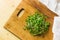 Bunch of daikon radish microgreen sprouts on the wooden cutting board close up. Radish green shoots at the kitchen table.