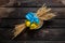 A bunch of ears of wheat lie on a wooden table tied in a bow with the flag of Ukraine, world famine war 2022