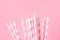 Bunch of Elegant White Striped Paper Drinking Straws on Pink Background. Birthday Party Babyshower Invitation Card Fun Kids