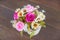 Bunch of flower in a vase is on the wooden floor / specific focus on pink rose.