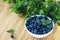 Bunch of fresh blueberry the white bowl on wooden background