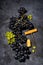 Bunch of fresh grapes and a corkscrew on a dark background, vertical top view