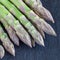 Bunch of fresh green asparagus on  dark slate background, square format