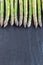 Bunch of fresh green asparagus on dark slate background, vertical, copy space