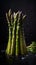 Bunch of fresh green asparagus spears with water drops on black background