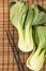 Bunch of fresh green baby bok choy with chopsticks , on bamboo placemat