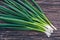 Bunch of fresh green onions on a feather on an old wooden table