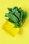 A bunch of fresh spinach in a yellow lunch box on a yellow background. Healthy eating concept. Plastic container. Green Spin