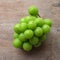 bunch of fresh sweet green shine muscat (vitis vinifera) grape isolate on a wooden background. japanese grapes.