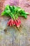 Bunch of freshly picked red & white organic variety french breakfast on wooden background.