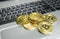 A bunch of golden bitcoin coin on a silver keyboard of laptop. Virtual cryptocurrency concept. Mining of bitcoins online