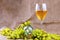 Bunch of grapes, glass bottle and glass of white wine on burlap fabric background