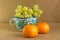 Bunch of grapes presented in a traditional hand-painted ceramic vase next to some tangerines