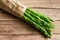 Bunch of green fresh asparagus tied with twine lying on aged plank wood table