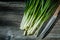 Bunch of green scallions and kitchen knife on vintage wood