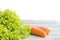 Bunch of lettuce leaves, carrots on a wooden background.