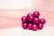 A bunch of magenta painted ornaments on a white surface mattress with a textured pink background