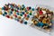 Bunch of many colorful thumbtacks as multi-color office supply metal pushpins circles in yellow, green, blue, red and white desk