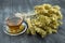 Bunch of mountain tea Malotira and mug with hot tea. Mountain tea sideritis. Natural Greek herbs on dark wooden background