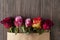 Bunch of multicolor rose flowers in paper envelope over wooden b