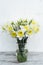 Bunch of narcissus in transparent vase on wooden table