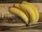 A bunch o yellow and spotted brown bananas on a wood grain backdrop