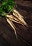 Bunch of parsnips with green leaves on dark wooden desk