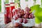 A bunch of pink grapes, prepared to extract the juice, is in a white basket . Two bottles of grape juice are on the table next to