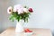 Bunch of Pink peonies in vase and strawberry on the wooden table . Flowers on a beige wooden table near the window. Home